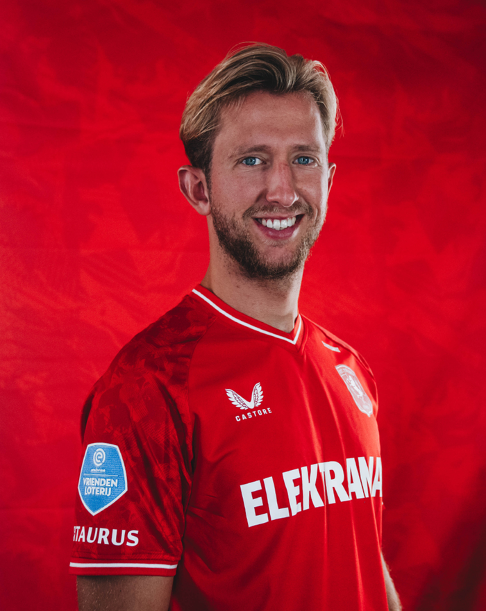 Front view of FC Twente home shirt 23/24 for men in red with white trimmed V neck, club crest on left chest and Castore logo on right