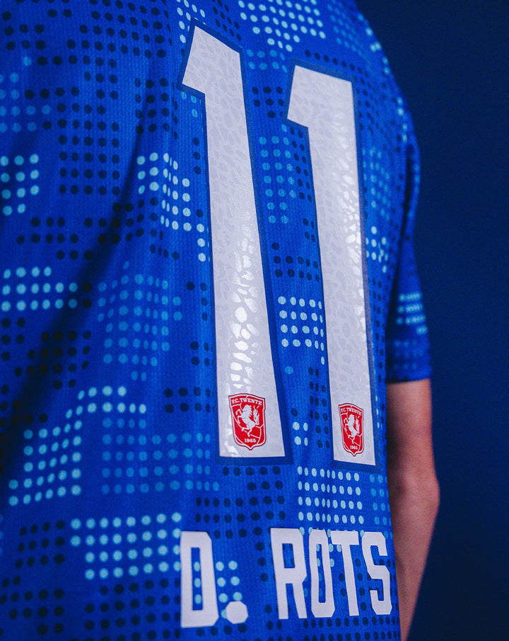 Back view of blue FC Twente 25/26 away shirt with large white number 11 and two club crests.