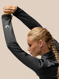 Model in Flow Training Top with long sleeves, arms raised, logo visible on the left sleeve.