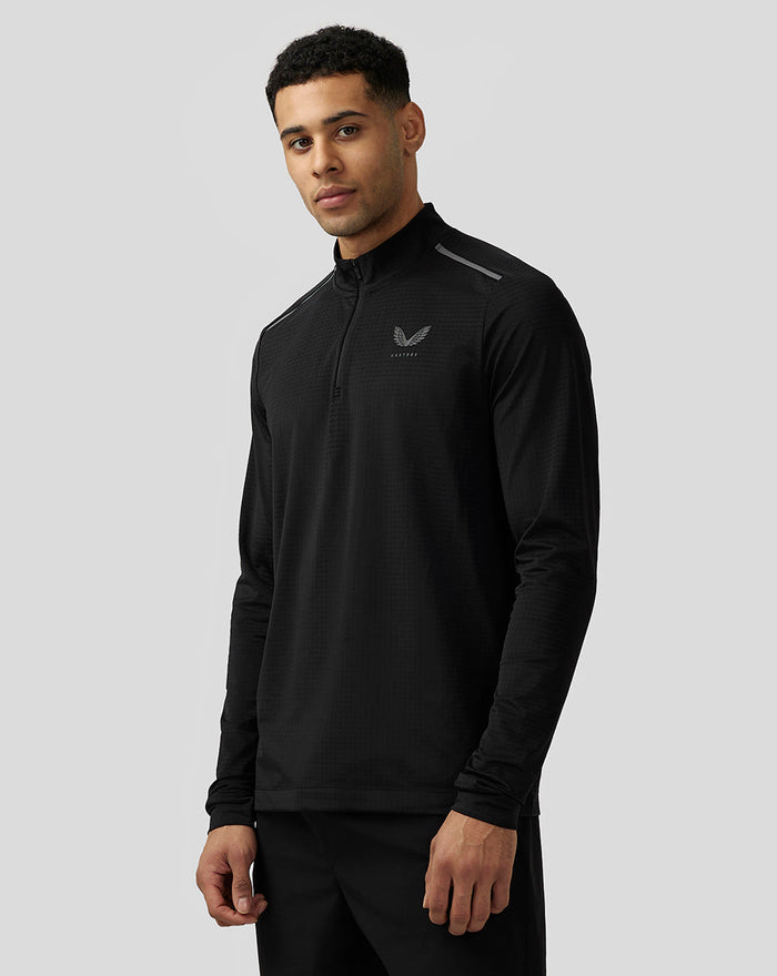 Man wearing black Apex Aeromesh quarter zip top with long sleeves and reflective Castore branding on the chest