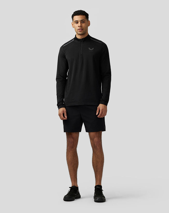 Male model wearing black Apex Aeromesh Top with funnel neck and quarter zip, reflective Castore logo on the left chest.