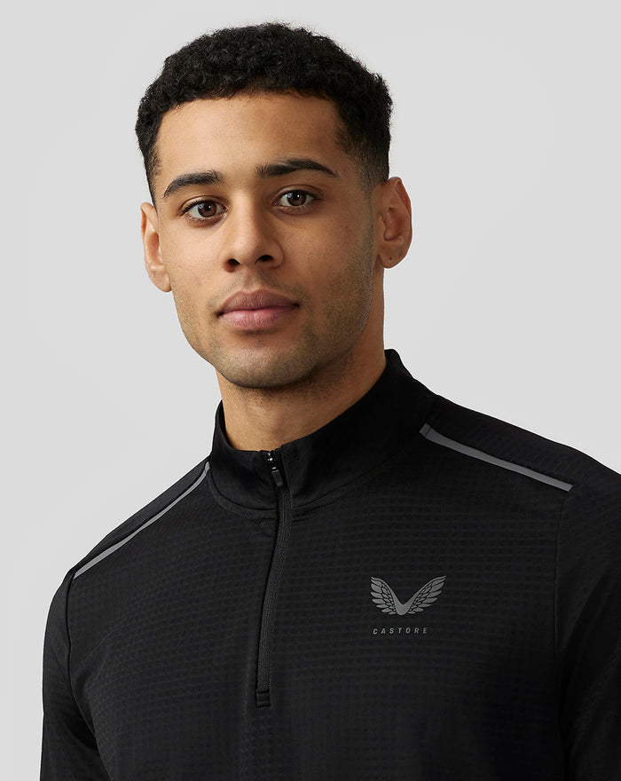 Close-up of a man in a black Apex Aeromesh top with a reflective Castore logo on the left chest.