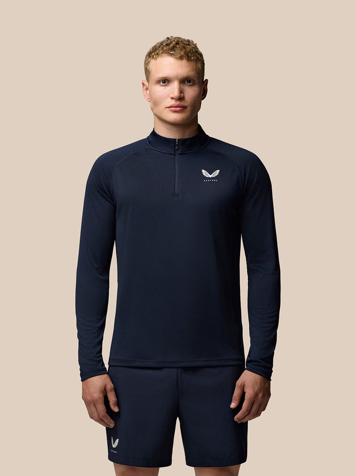 Male model in navy Adapt Training long sleeve ¼ zip top with Castore branding on chest and upper back.