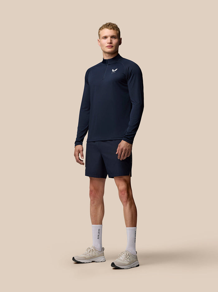 Male model wearing navy Adapt Training 1/4 Zip Top with Castore logos on left chest and upper back