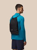 Model wearing a black Castore gym bag as a backpack over a teal athletic top