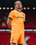 FC Twente goalkeeper jersey 26/27 in bright orange with black trim and club crest on shorts visible in stadium