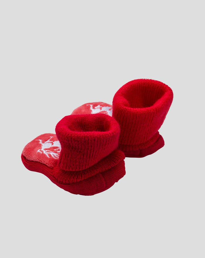 Pair of red knitted baby booties with crest and white trim