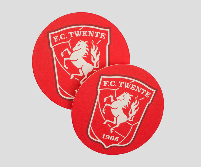 Two overlapping red FC Twente beer mats featuring the crest