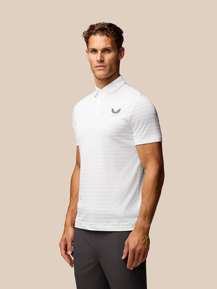 Male model wearing a white Golf Pinnacle Pique Stripe Polo with subtle horizontal stripes and a small chest logo.