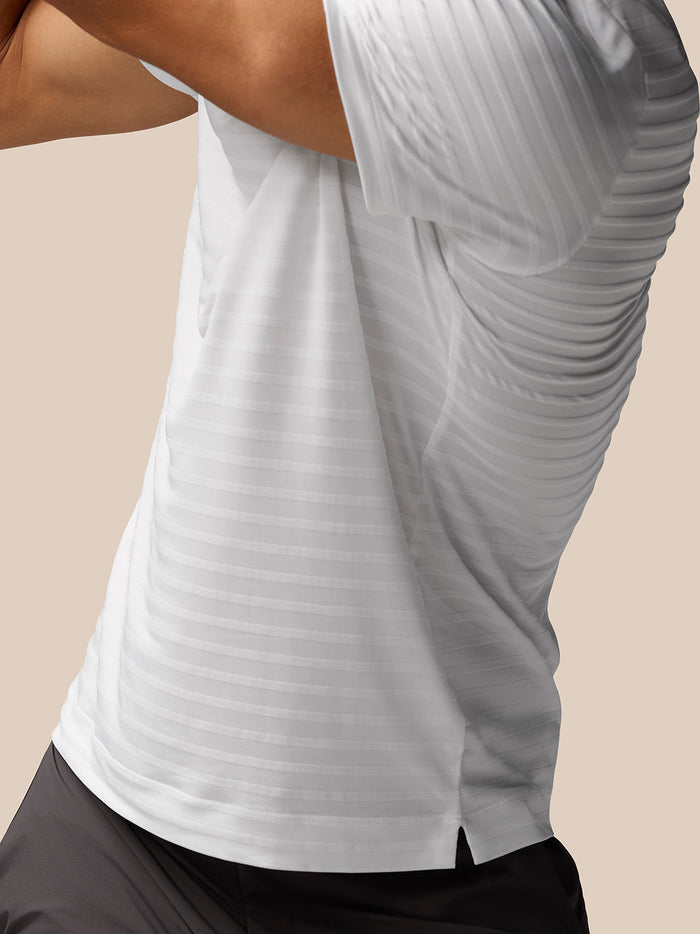 Close up of the side of a white Golf Pinnacle Pique Stripe Polo showing textured stripes and a side hem vent