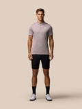 Full-body shot of a male model wearing a pink striped golf polo with Castore logo on the chest and black shorts