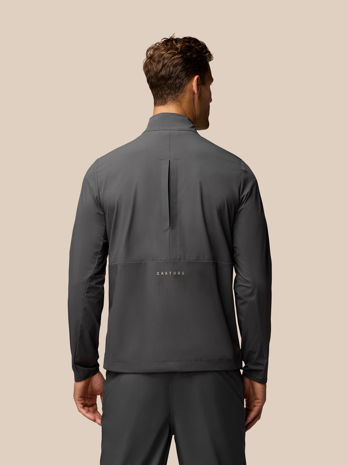 Achterkant van gunmetal golf top met verticale opening en Castore-logo op de onderrug.