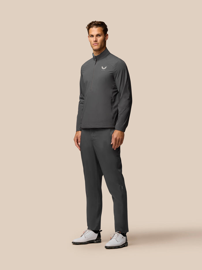 Full-body shot of a man wearing a gunmetal golf top with stand collar and half-zip, matching pants.