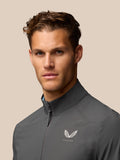 Close-up detail of gunmetal golf top with zipper and Castore logo on left chest.