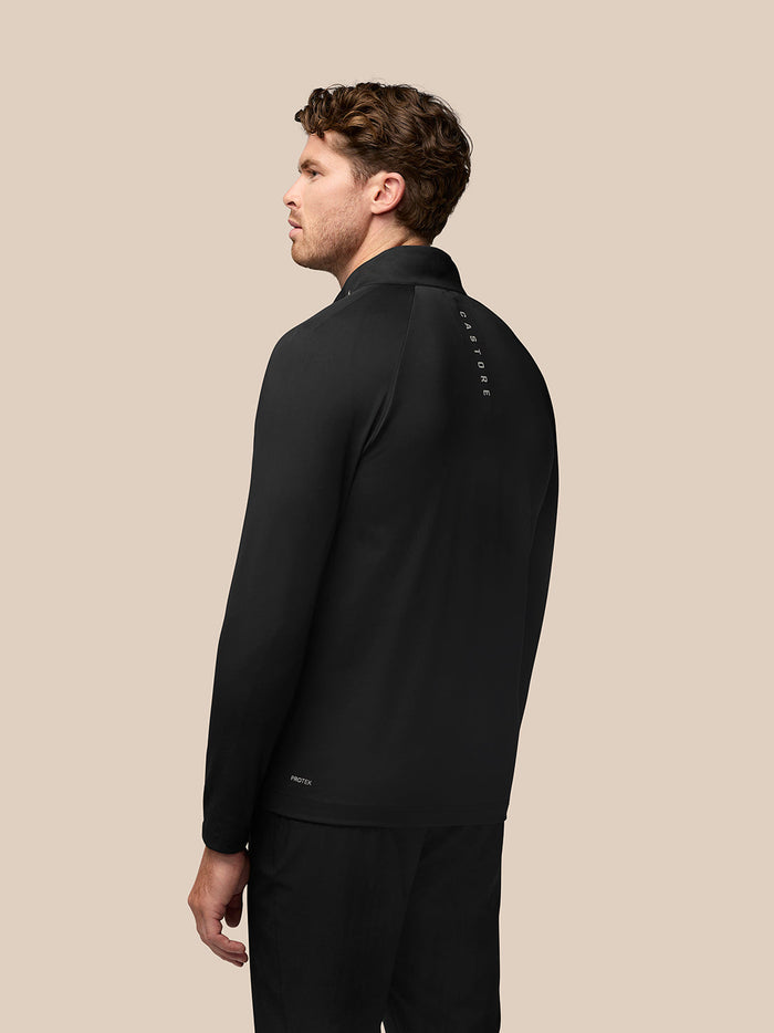 Back view of a man in a black Pinnacle hybrid golf jacket with a standing collar and CASTORE logo along the upper back