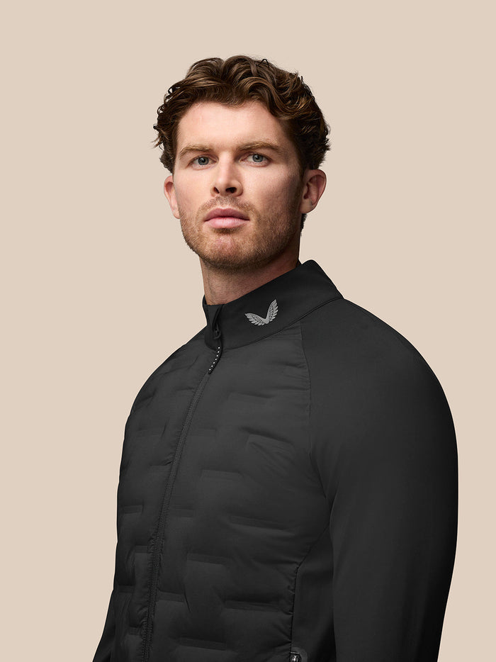 Man wearing black Pinnacle Hybrid Golf Jacket with stand up collar and quilted front panels
