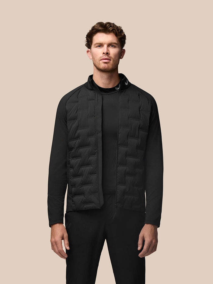 Male model wearing black Pinnacle hybrid quilted golf jacket with full front zipper and a standing collar