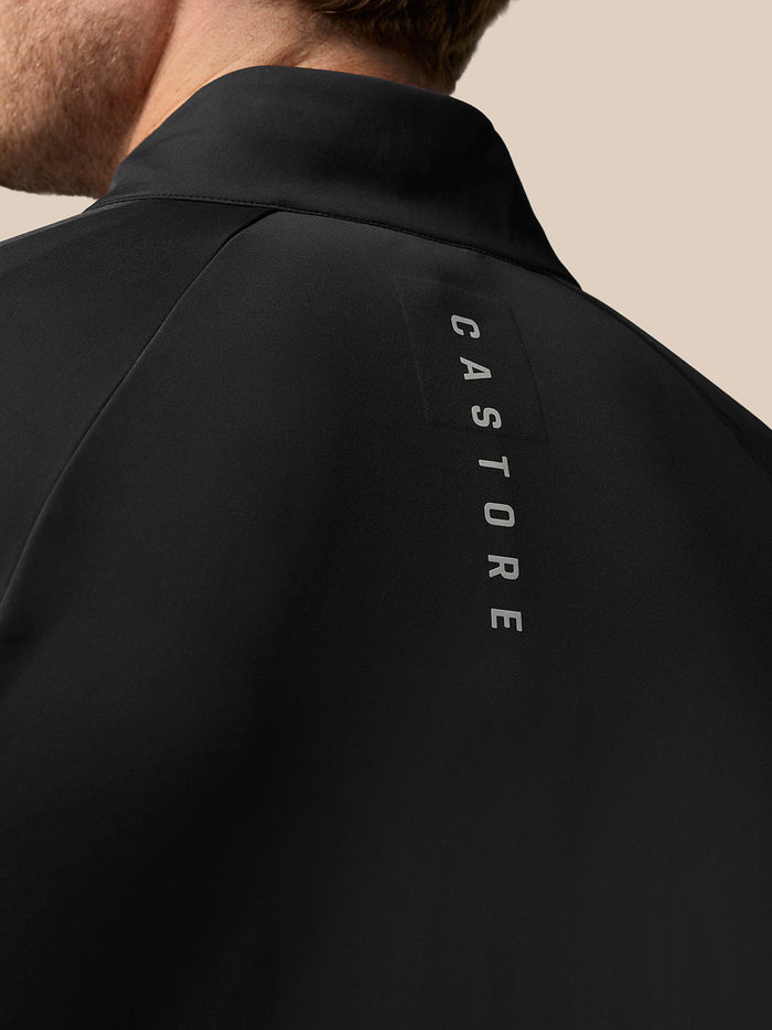 Back view of black Pinnacle Hybrid golf jacket with vertical GASTORE lettering along the upper back.