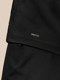 Lower back close-up of the black jacket showing PROTEK branding on the hem.