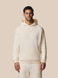 Model draagt Heren Adapt lange mouwen katoenen fleece hoodie in oatmeal marl met geborduurd Castore-logo op borst