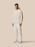 Full-body side view of model in oatmeal fleece hoodie with hood and matching joggers small logo on chest