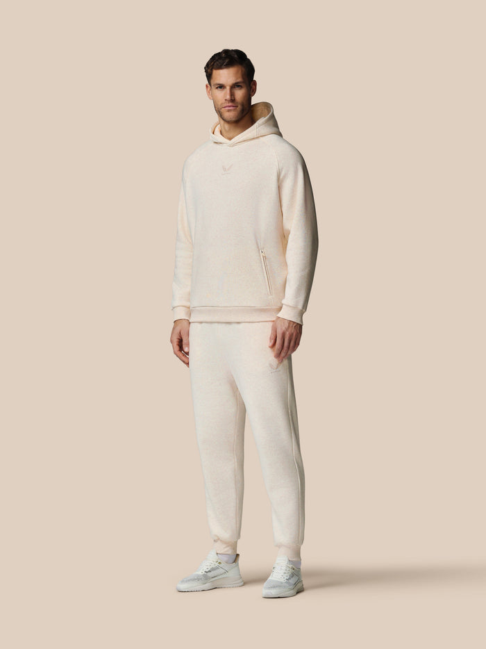 Full-body side view of model in oatmeal fleece hoodie with hood and matching joggers small logo on chest