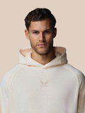 Close-up van model met oatmeal marl hoodie, geborduurd Castore-logo op borst zichtbaar