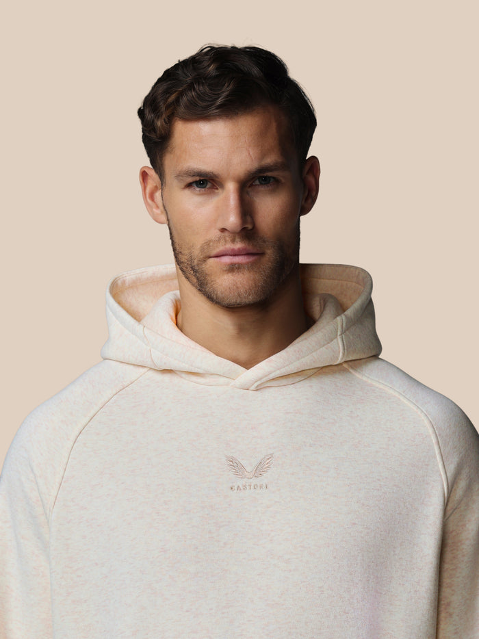 Close-up van model met oatmeal marl hoodie, geborduurd Castore-logo op borst zichtbaar