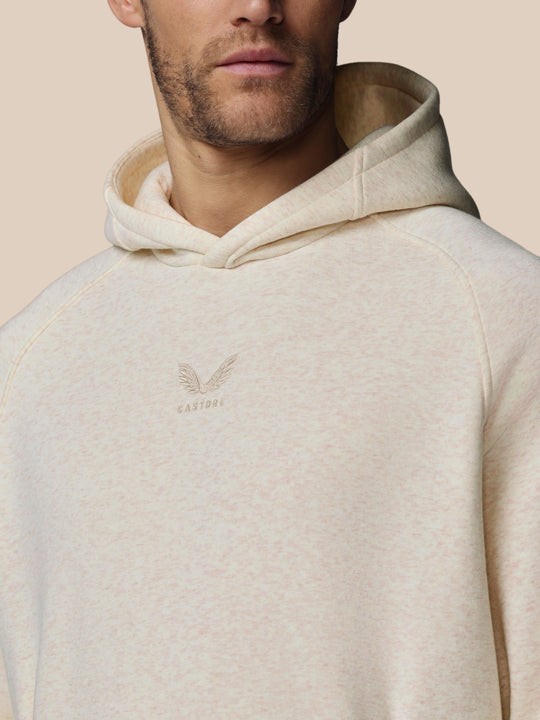 Nauwe close-up van oatmeal marl hoodie met geborduurd Castore-logo op borst