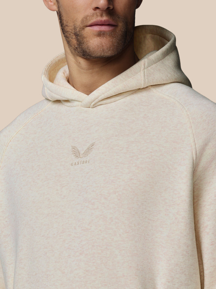 Nauwe close-up van oatmeal marl hoodie met geborduurd Castore-logo op borst