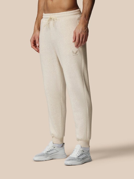 Beige oatmeal fleece joggers with Castore logo on left thigh and drawstring waist