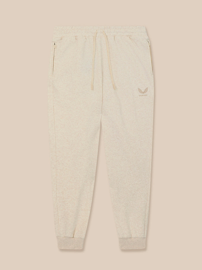 Front view of beige fleece joggers with drawstring waist and ribbed cuffs, featuring an embroidered Castore logo on the left thigh.