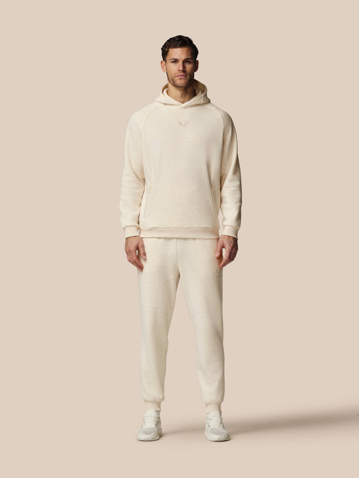 Full length model wearing beige fleece tracksuit hoodie and joggers with Castore logo on chest