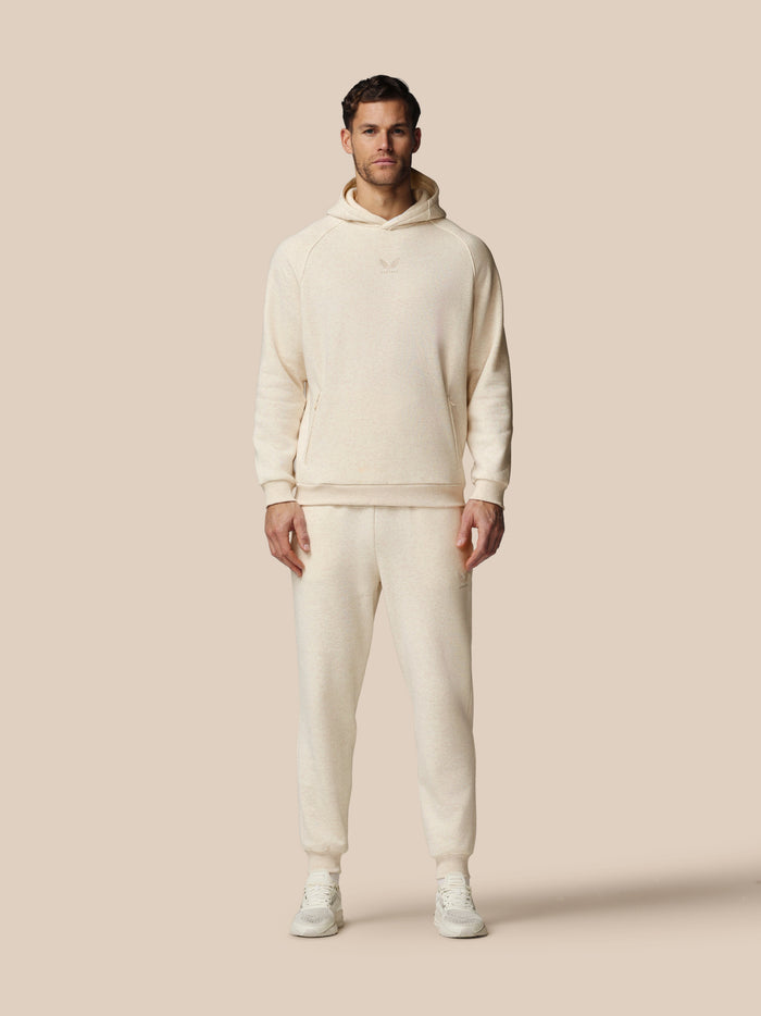 Full length model wearing beige fleece tracksuit hoodie and joggers with Castore logo on chest