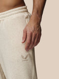 Close-up view of beige fleece joggers with an elastic waistband and embroidered Castore logo on the left thigh.