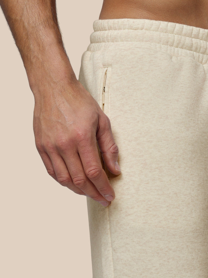Beige fleece joggers close-up at the hip showing a zippered side pocket.