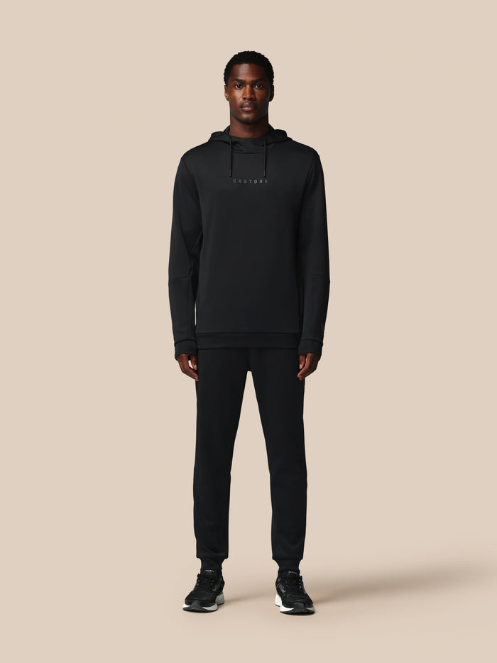 Vooraanzicht van man in zwarte Flex hoodie met capuchon en Castore logo op de borst