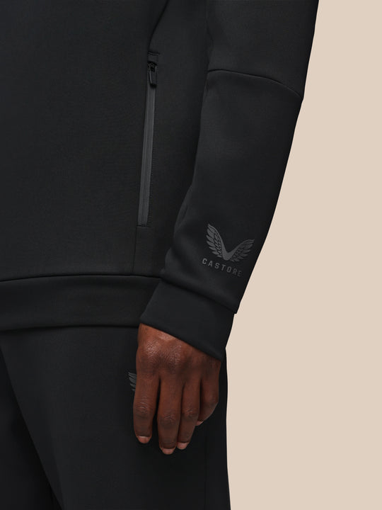Close up of black Castore Flex hoodie sleeve showing a side zip and the Castore wing logo on the wrist.
