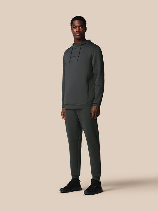 Male model wearing a dark green hoodie and matching joggers, full body product shot