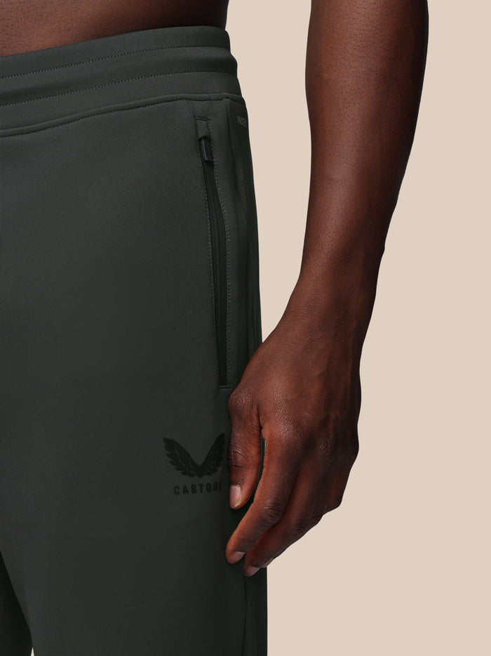 Close up of zipped side pocket on dark joggers with Castore logo on the thigh