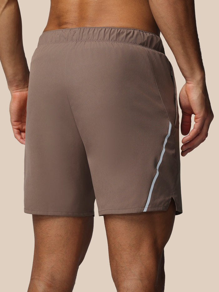 Diep taupe 6 inch herenshort met binnenslip en lichtgrijze piping langs de zijkant, Castore logo op dij