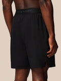 Back view of a male model wearing black Adapt Training Shorts with branded elastic waistband