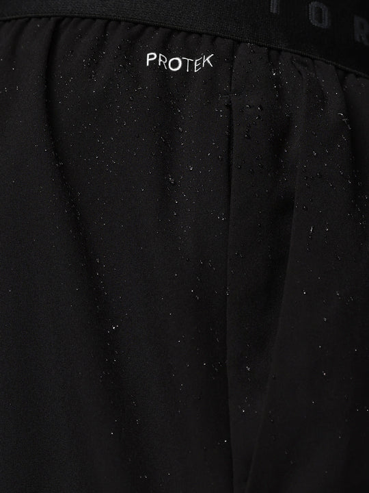 Close up of black shorts waistband showing CASTORE branding and water droplets on fabric.