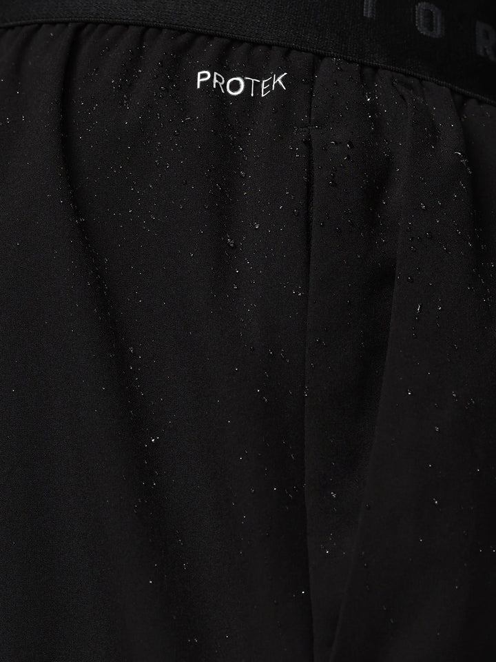 Close up of black shorts waistband showing CASTORE branding and water droplets on fabric.