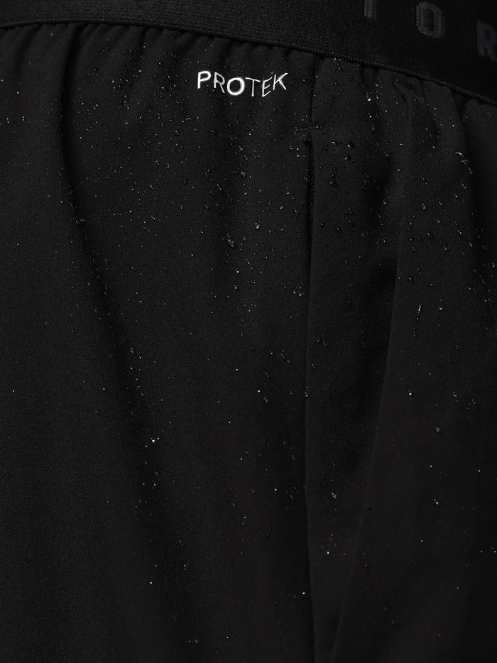 Close up of black shorts waistband showing CASTORE branding and water droplets on fabric.