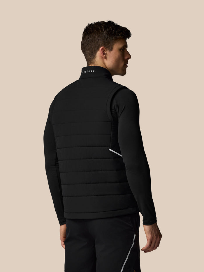 Achteraanzicht van een man in zwarte Apex Training Gilet met Castore woordmerk op de kraag