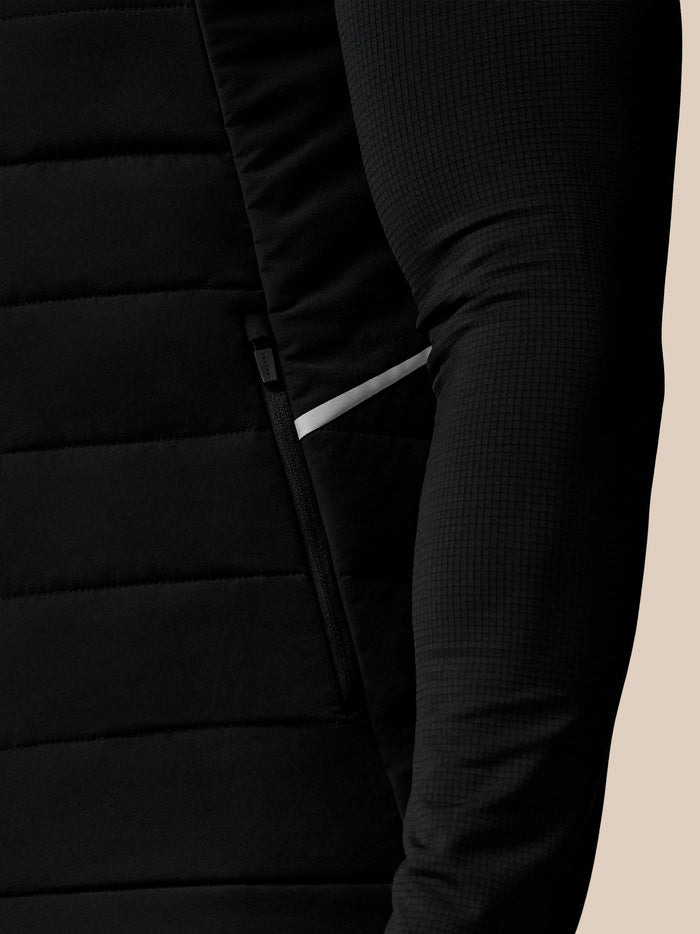 Close up of black Apex Gilet lower side showing reflective stripe and textured fabric