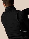 Back collar of a black Apex Gilet with white Castore text against a beige background