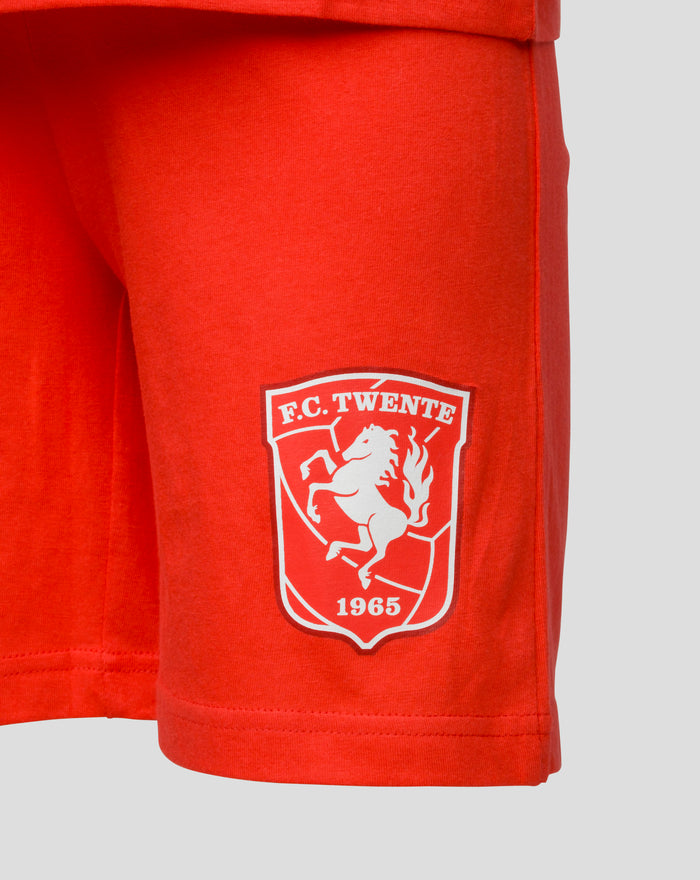 Close up of red FC Twente shorts fabric with a white crest badge.