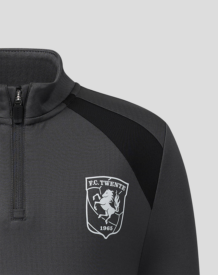 Close-up of FC Twente crest on chest of gunmetal midlayer top with zipper collar.